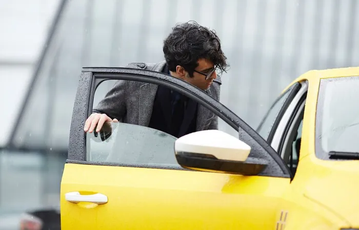 A man opening the door of a yellow taxi to get in